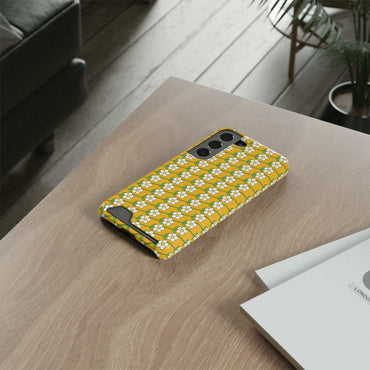Yellow floral phone case with white flowers and built-in card holder on wooden table