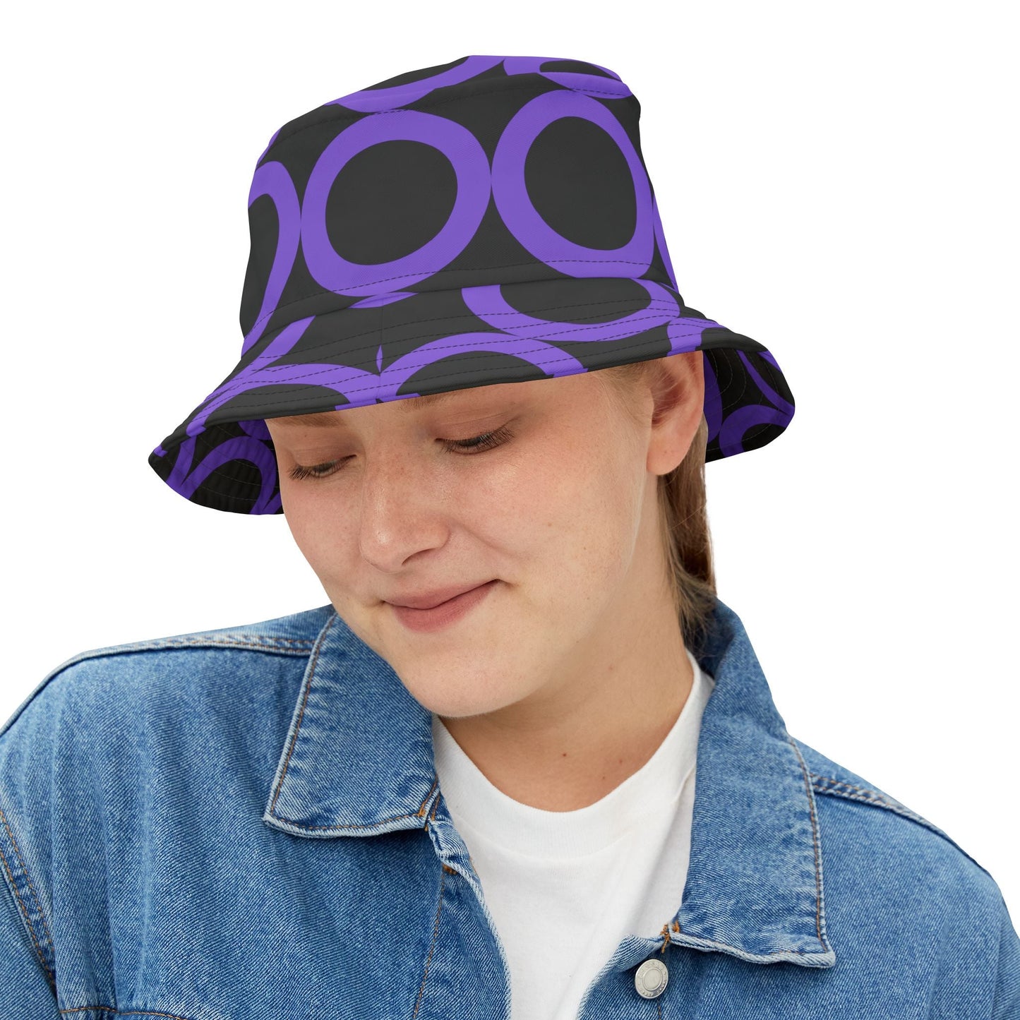 Woman wearing purple dot pattern bucket hat with black background and denim jacket