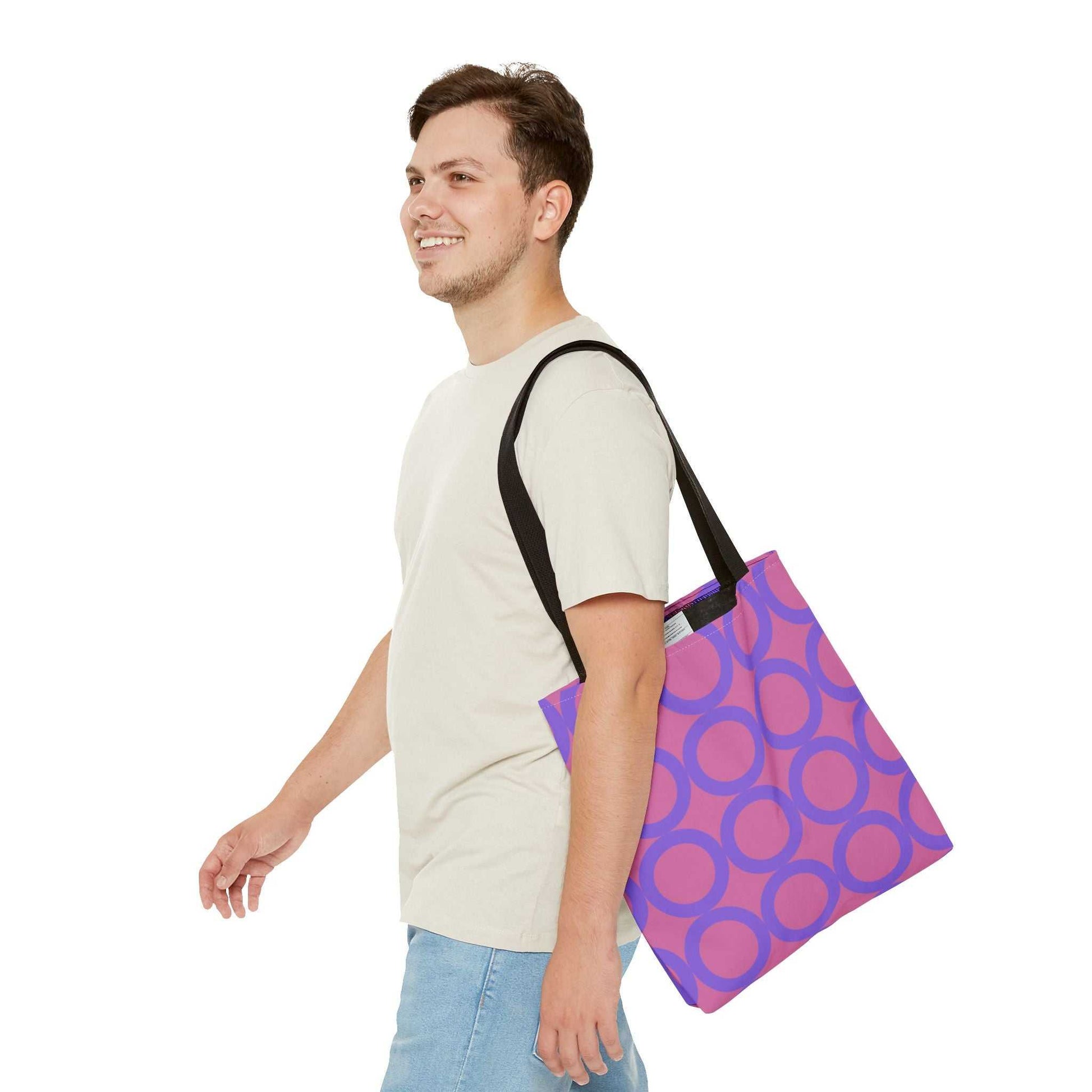 Man carrying chic light pink and purple circle tote bag with black handles over shoulder
