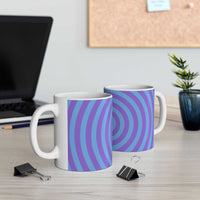 Two vibrant spiral ceramic mugs with blue and purple concentric circle design on a desk near a laptop and plant