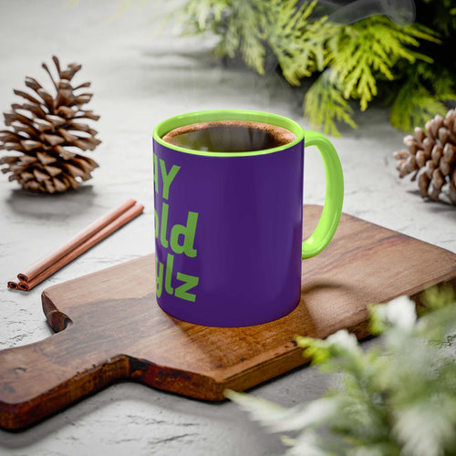 Colorful custom mug with green handle and interior, purple exterior with green text, steaming coffee inside on wooden board with pinecones and greenery background