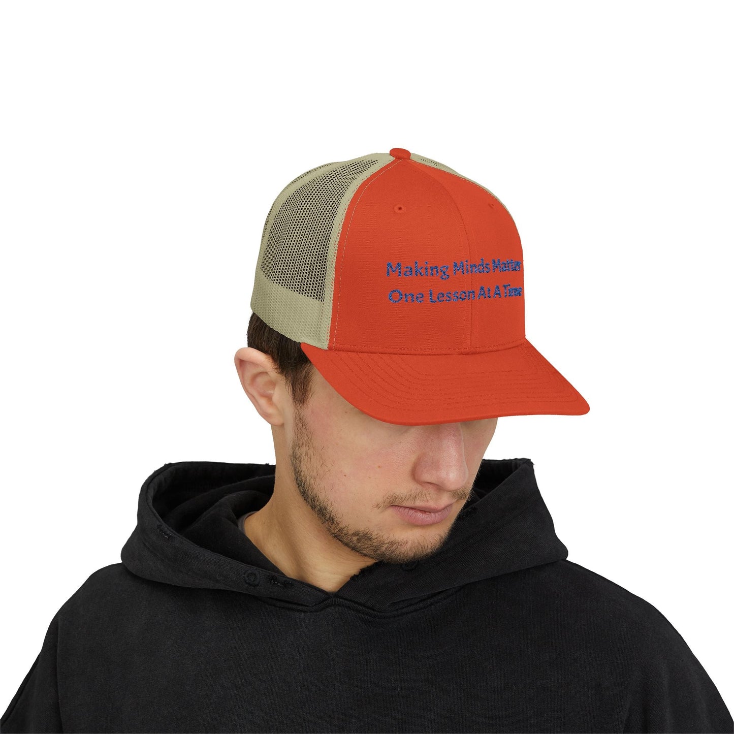 Man wearing orange and beige snapback trucker cap with blue text "Making Minds Matter One Lesson At A Time" and black hoodie
