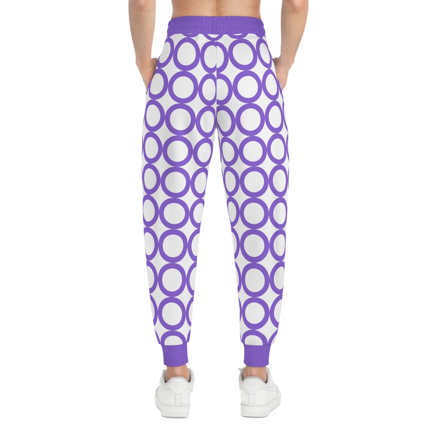 Stylish athletic joggers with purple circle print, adjustable drawstring waist, and side pockets, worn with white sneakers.