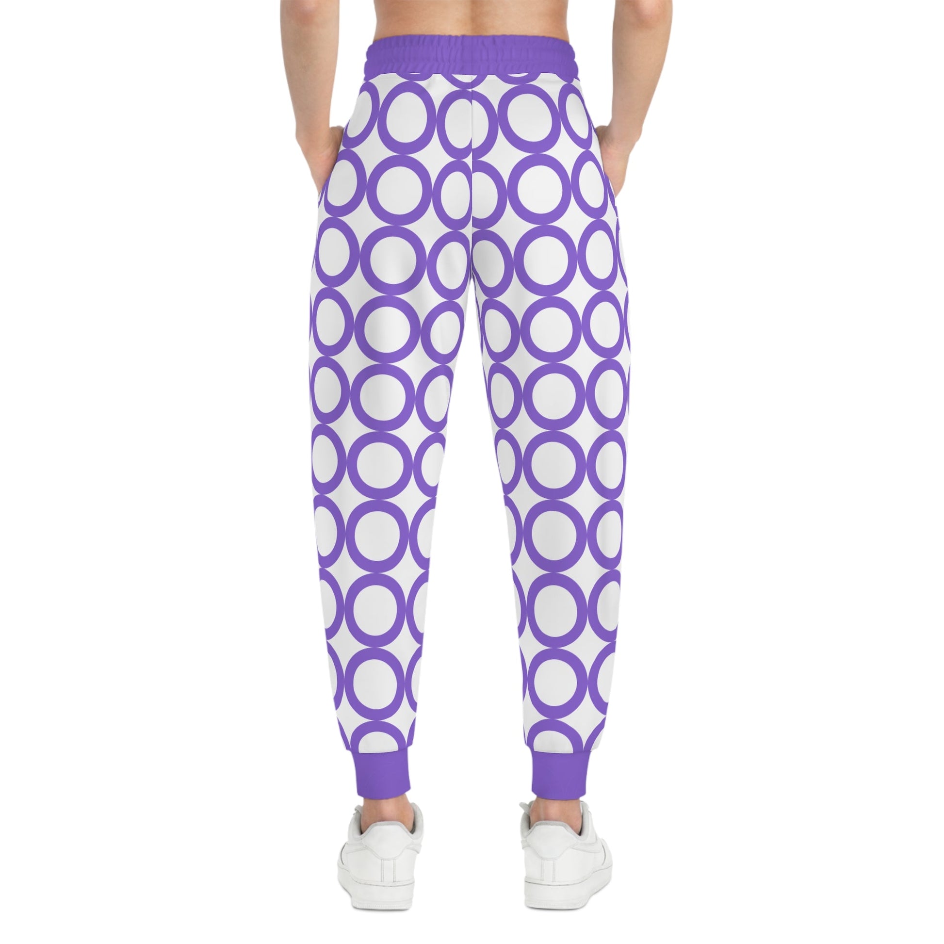 Stylish athletic joggers with purple circle print, adjustable drawstring waist, and side pockets, worn with white sneakers.