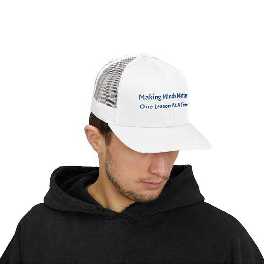 White snapback trucker cap with mesh back and embroidered text worn by a man in black hoodie