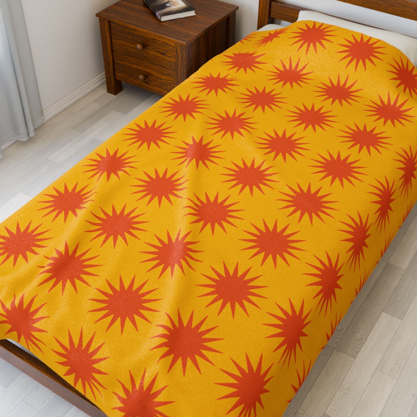 Cozy Velveteen Plush Blanket with vibrant orange star pattern on yellow background on bed in modern bedroom