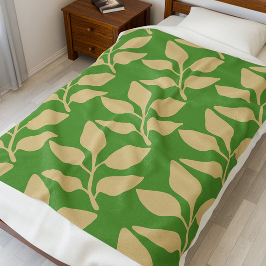 Velveteen plush blanket with green and beige leaf pattern on bed in cozy bedroom