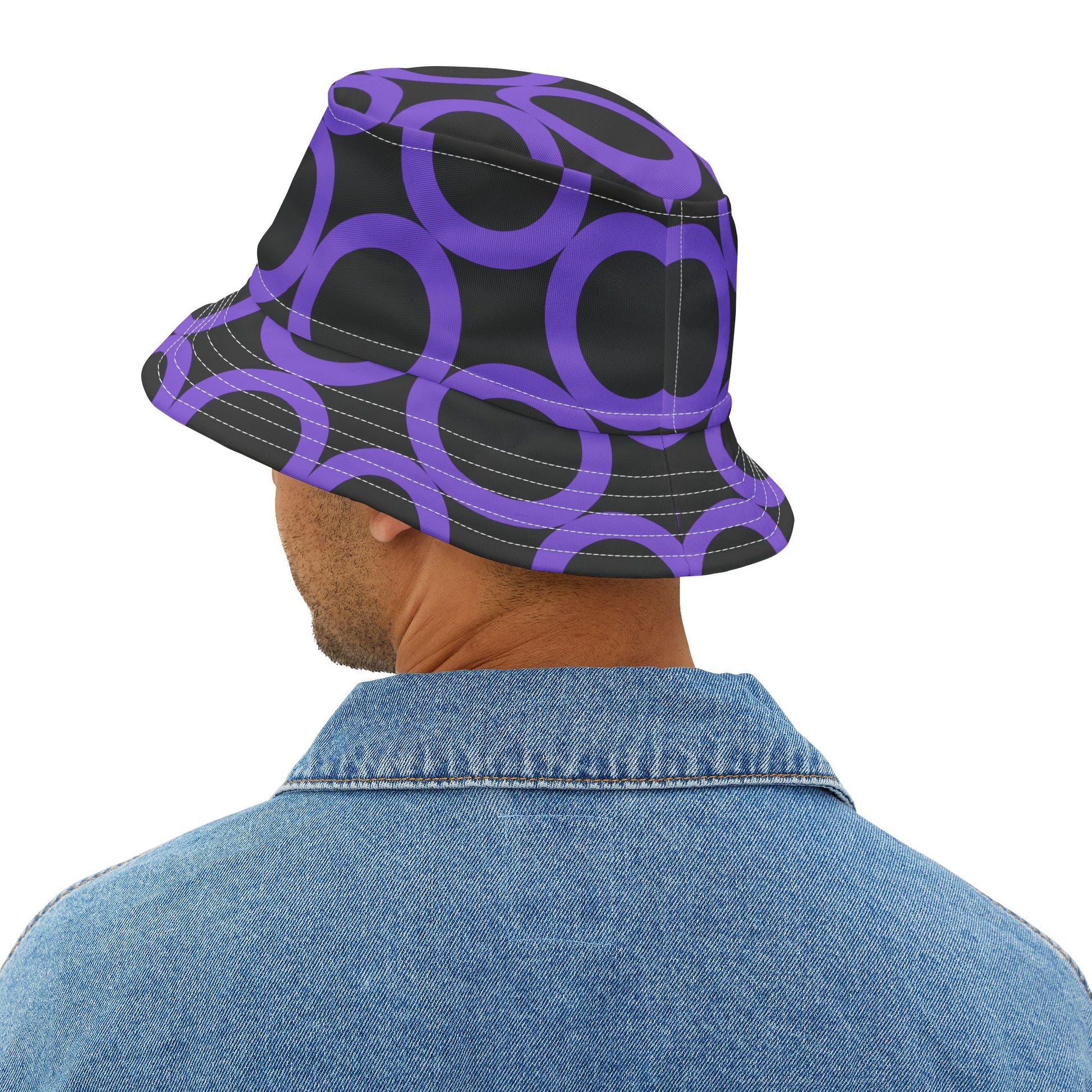 Man wearing purple dot pattern bucket hat with adjustable fit and denim jacket, black background