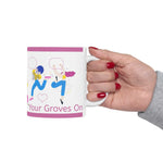 Hand holding Get Your Groves On ceramic mug with colorful dancing figures and pink accents