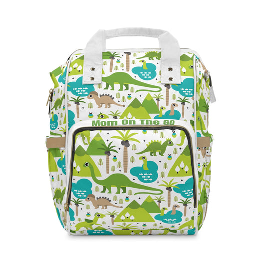 Dinosaur themed diaper backpack with green and blue dinosaur patterns, multiple compartments, and adjustable straps for toddlers and travel.