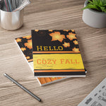Cozy Fall Notebook with autumn leaves design lying on wooden desk with pen and plant