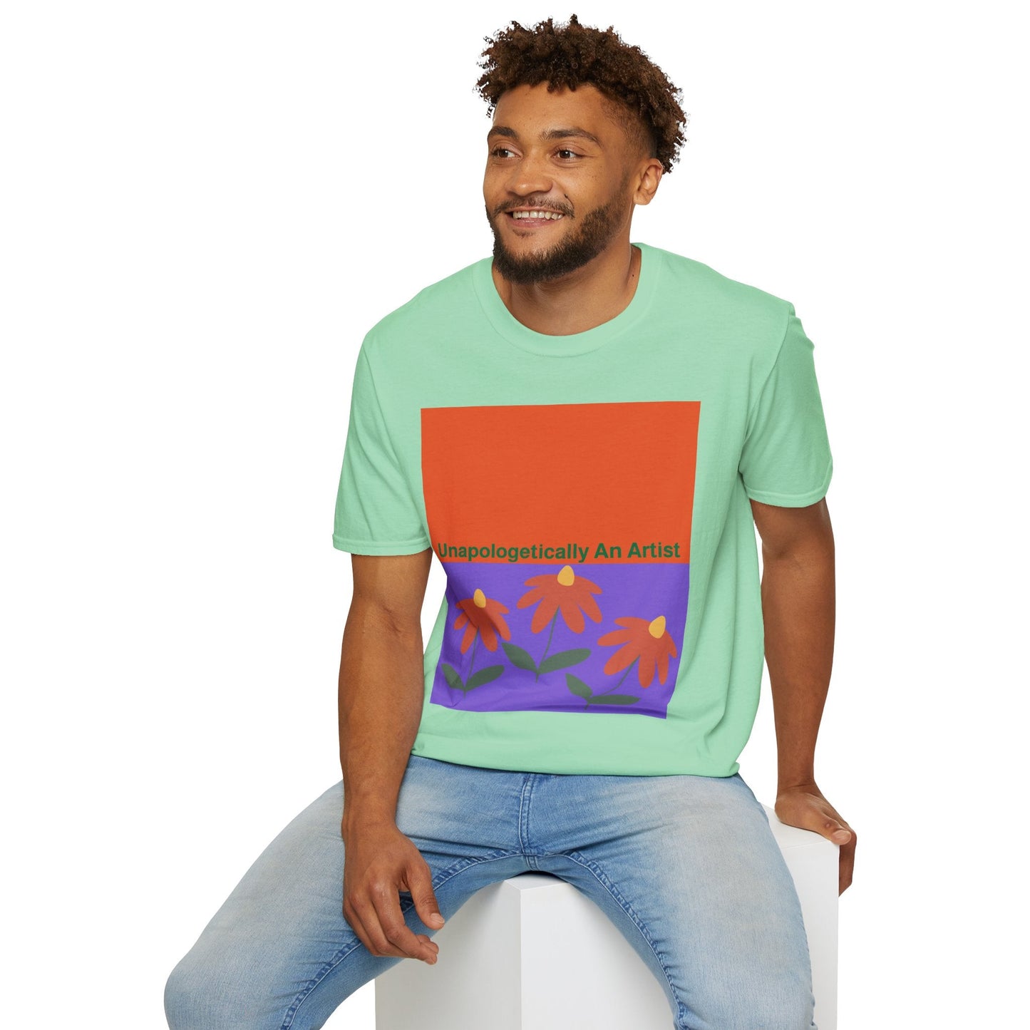 Man wearing mint green Unapologetically An Artist T-Shirt with floral design sitting on white block