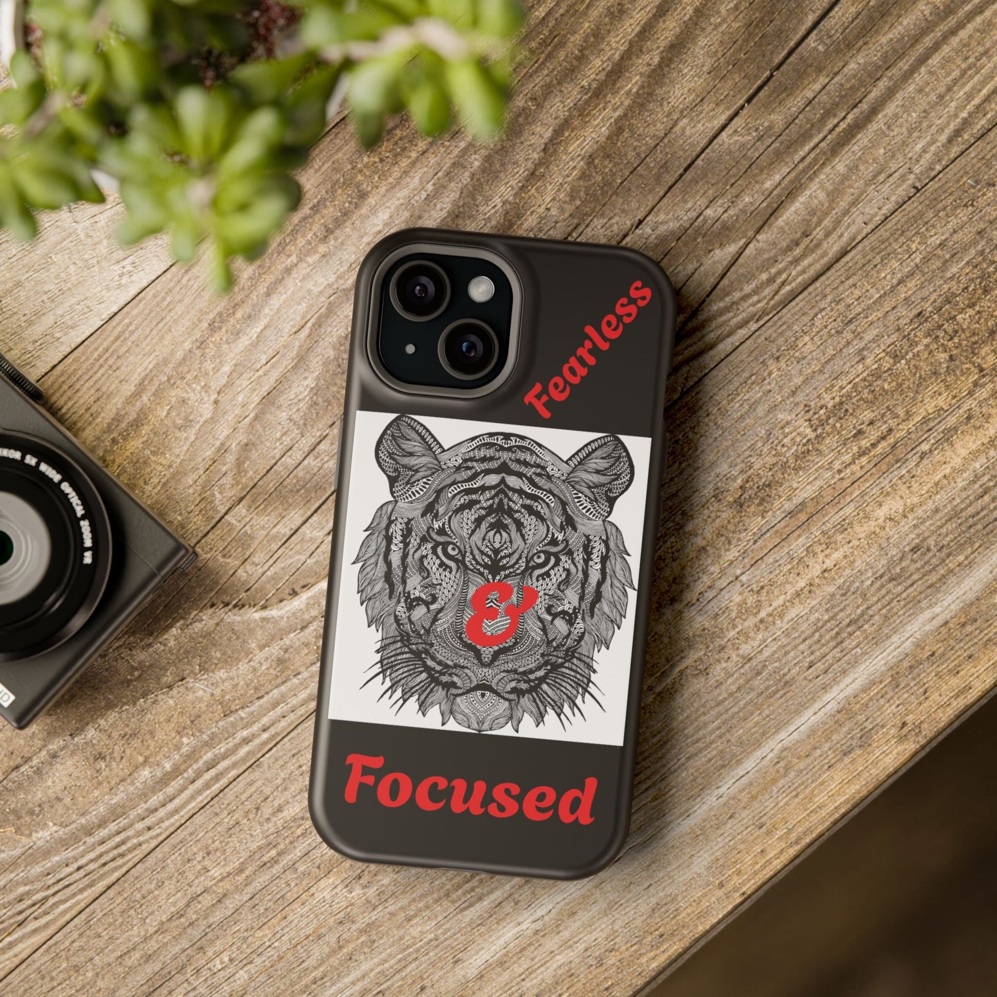 Tiger Phone Case with detailed tiger illustration and red fearless focused text, impact-resistant dual-layer protection, supports wireless charging, stylish accessory on wooden table.
