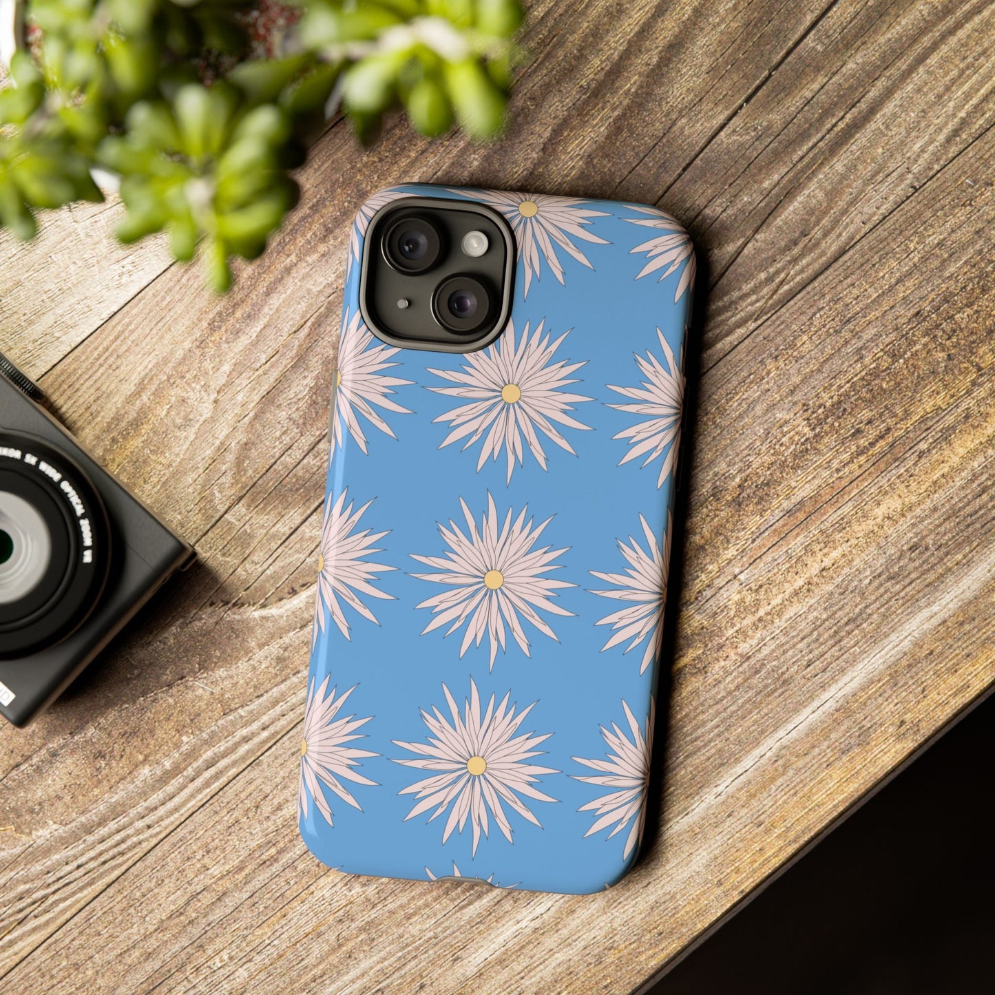 Blue phone case with white daisy pattern on wooden surface, stylish and durable protective cover