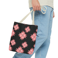 Colorful AOP Tote Bag with pink floral pattern on black background, held by person wearing light blue jeans, reusable shopping bag.