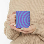Hand holding vibrant spiral ceramic mug with blue and purple swirl design