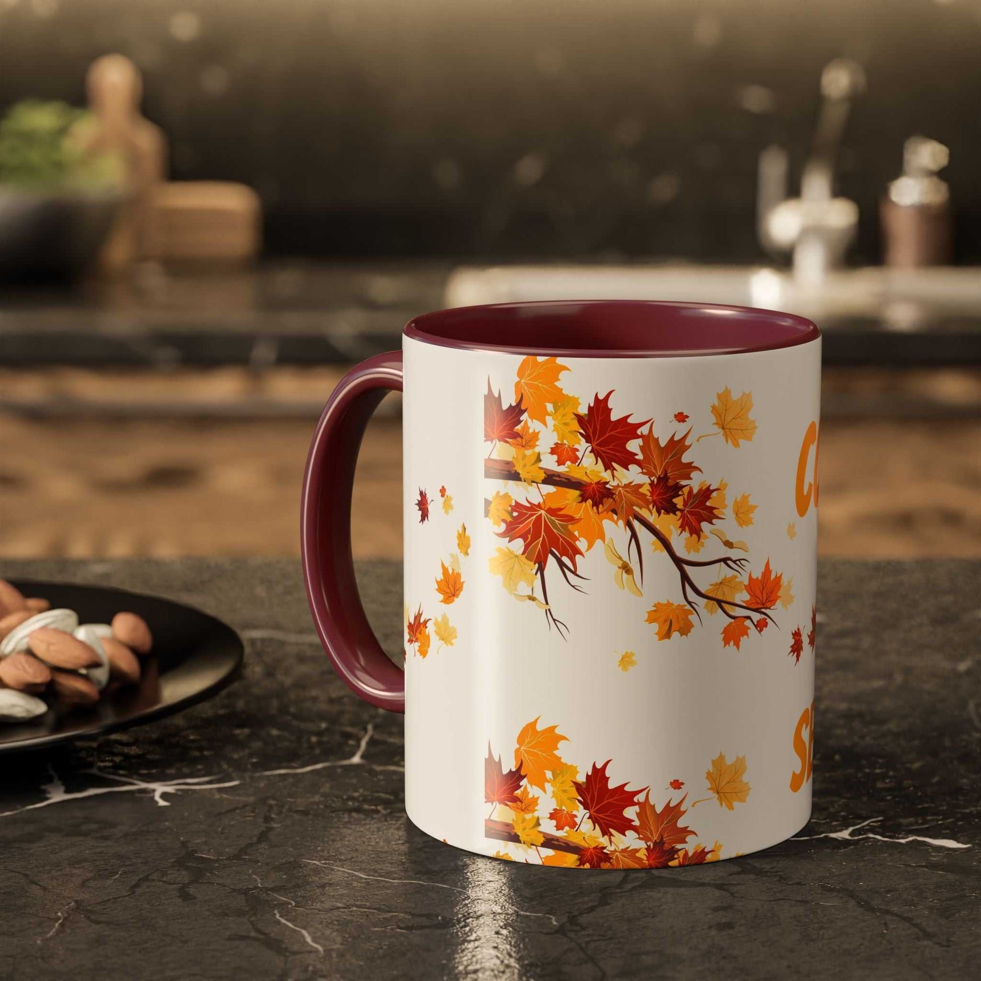 Fall Cozy Season Mug with colorful autumn leaves design and burgundy handle on kitchen countertop