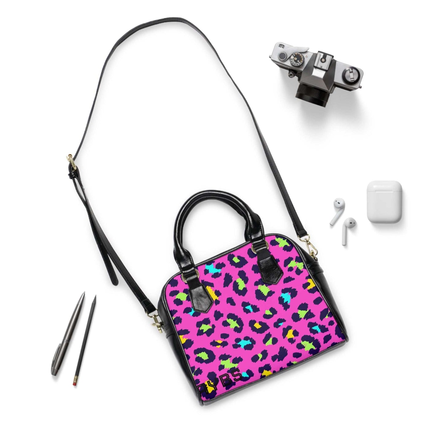 Vibrant leopard print shoulder handbag with adjustable strap and black handles on white background with camera and earphones