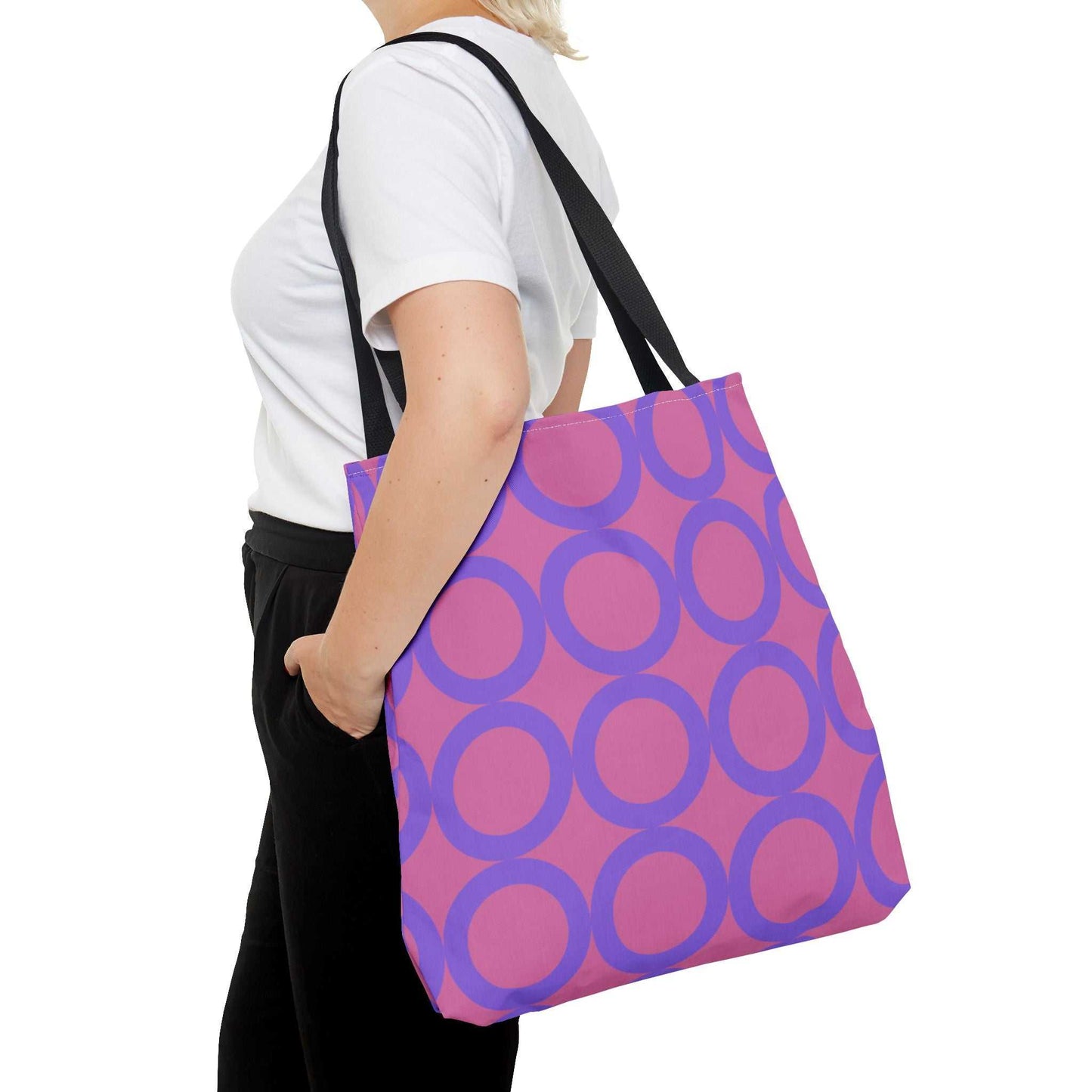woman carrying chic light pink and purple circle tote bag with black handles over shoulder