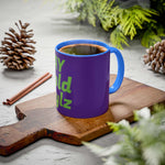 Colorful custom mug with blue handle and vibrant purple body, featuring green text, filled with steaming coffee on a wooden board surrounded by pinecones and greenery.