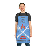 Man wearing blue apron with BBQ team design and black straps standing smiling