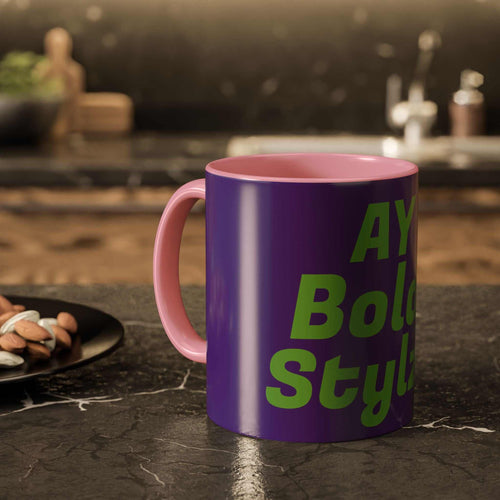 Colorful custom mug with purple exterior and pink interior, featuring bold green text, on a kitchen counter.