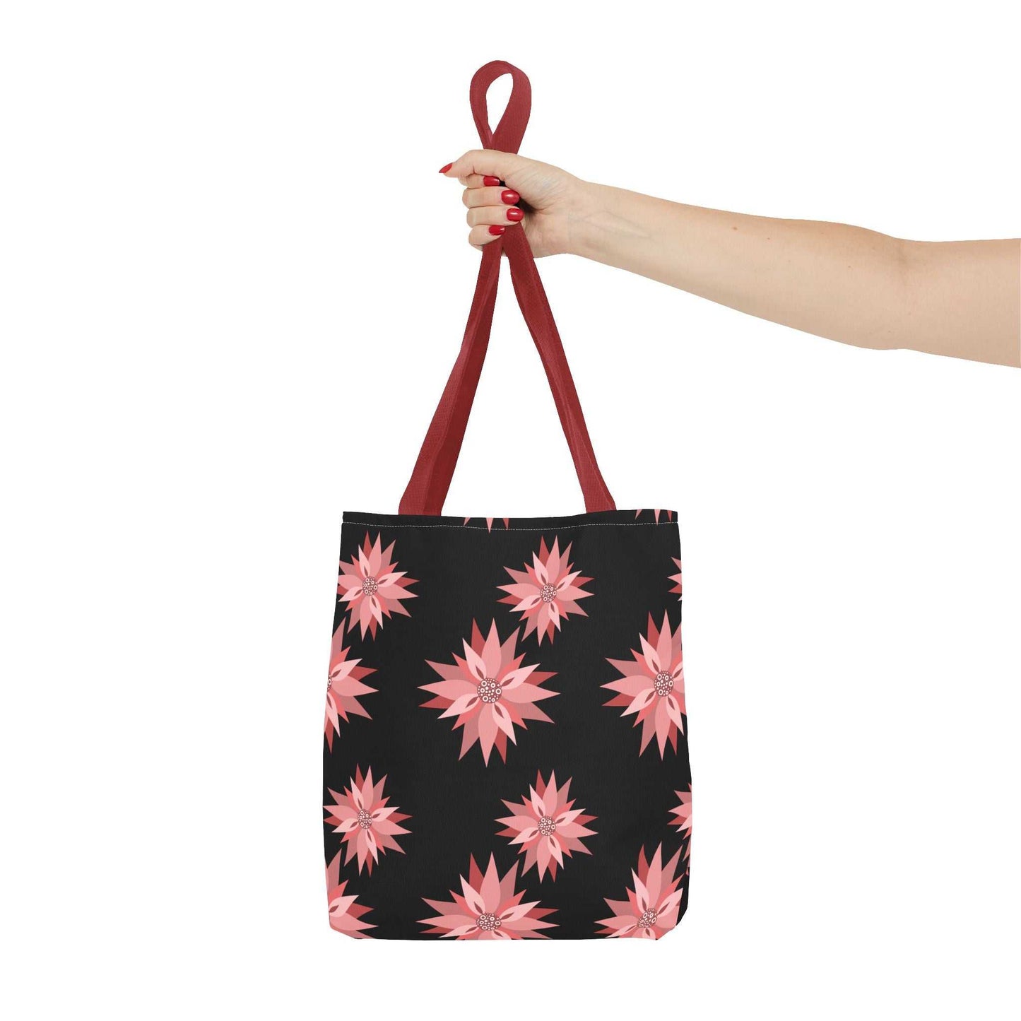 Colorful AOP Tote Bag with pink floral pattern and red handles held by hand, reusable shopping bag