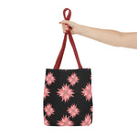 Colorful AOP Tote Bag with pink floral pattern and red handles held by hand, reusable shopping bag