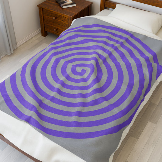plush blanket with purple spiral design on bed in cozy bedroom setting