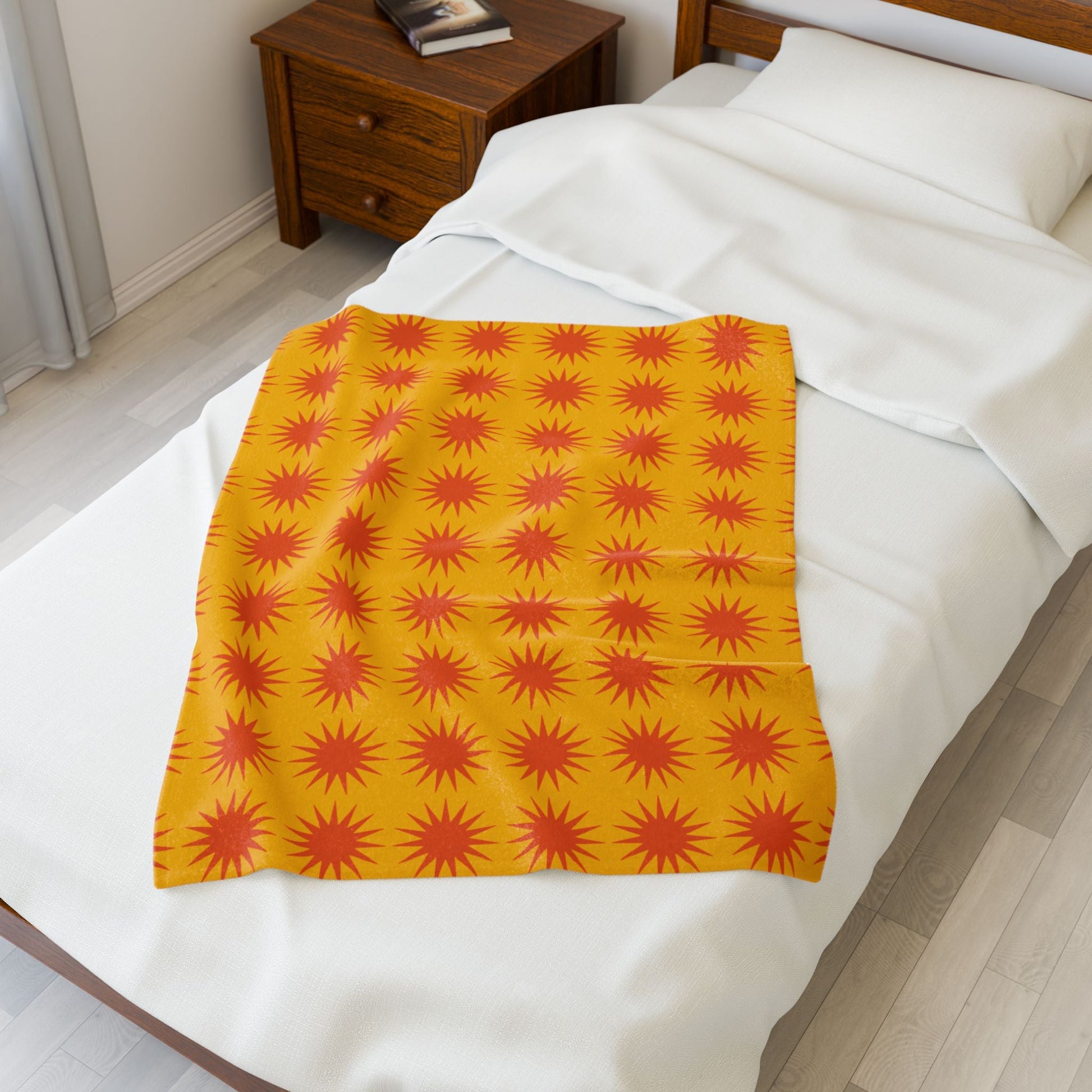 Cozy velveteen plush blanket with vibrant orange starburst pattern on bed for home decor and warmth