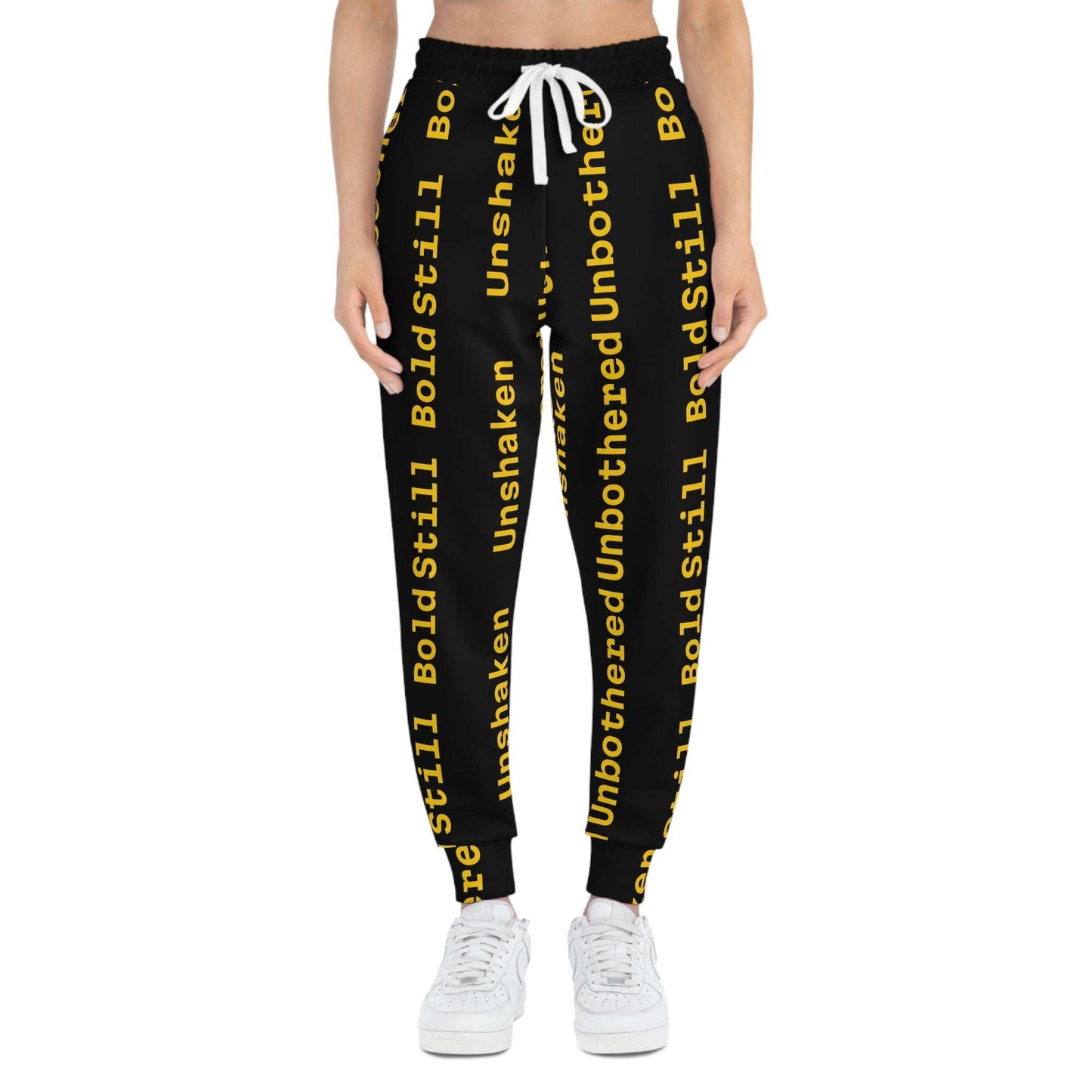 Eco-friendly black joggers with yellow "Unbothered Unshaken Bold Still" text, adjustable white drawstring waist, and side pockets.