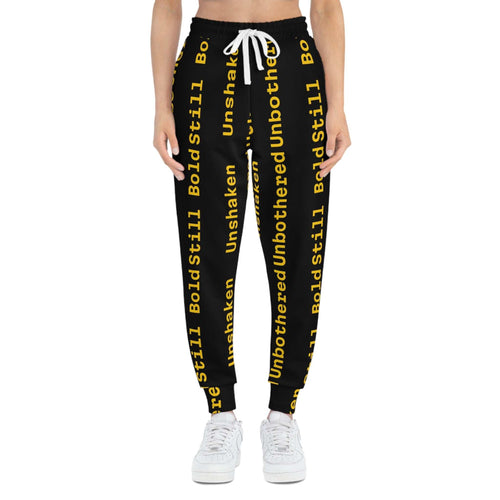 Eco-friendly black joggers with yellow "Unbothered Unshaken Bold Still" text, adjustable white drawstring waist, and side pockets.