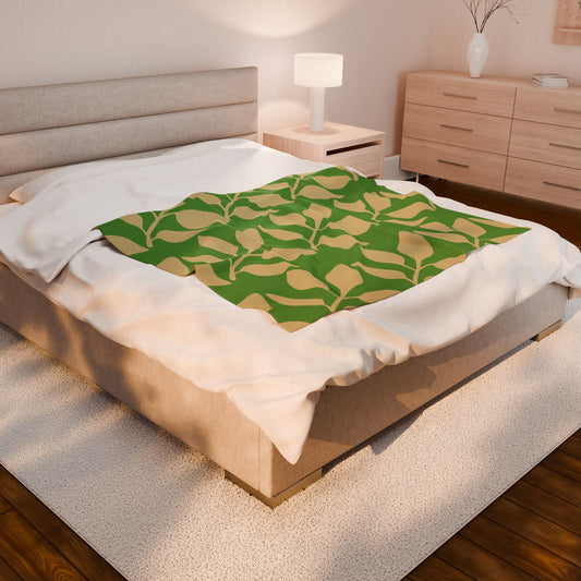 Velveteen plush blanket with green leaf pattern on bed in cozy bedroom setting