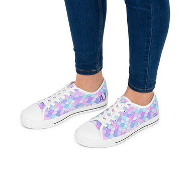 Women's pastel mermaid print low top sneakers with white toe caps and laces worn with dark blue jeans