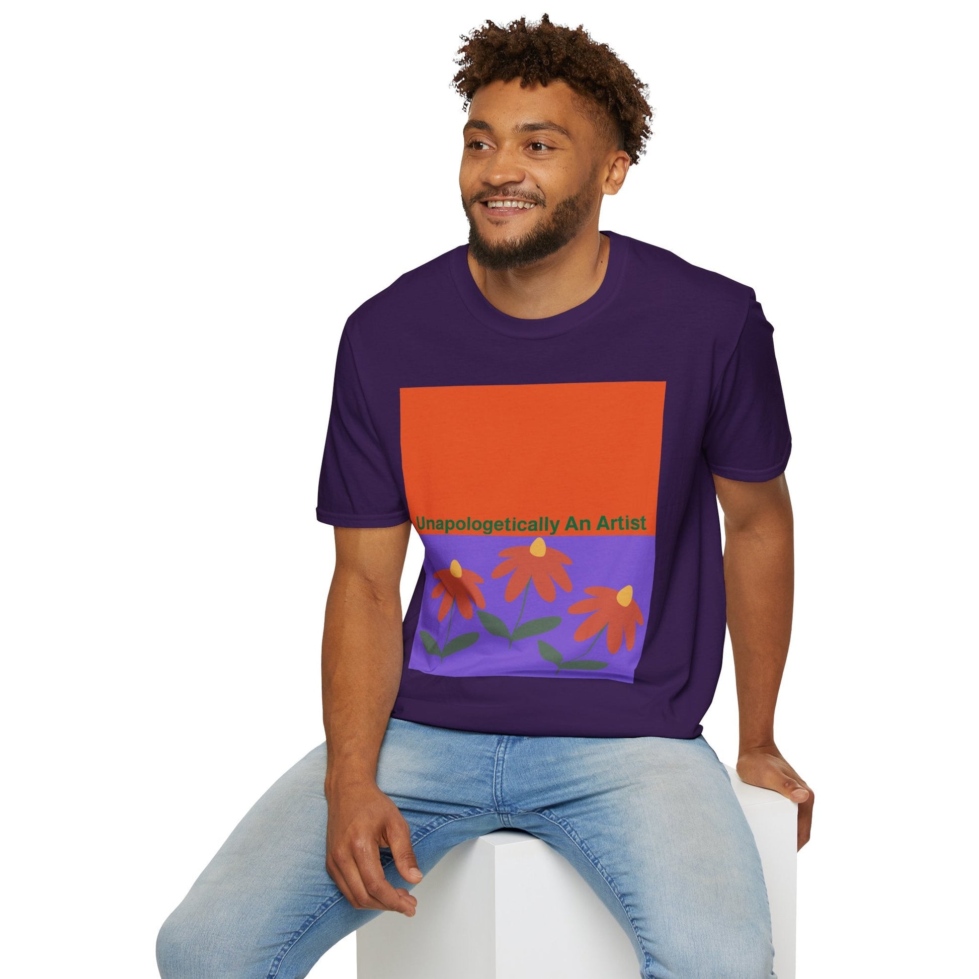 Man wearing purple Unapologetically An Artist T-Shirt with floral design sitting on white cube