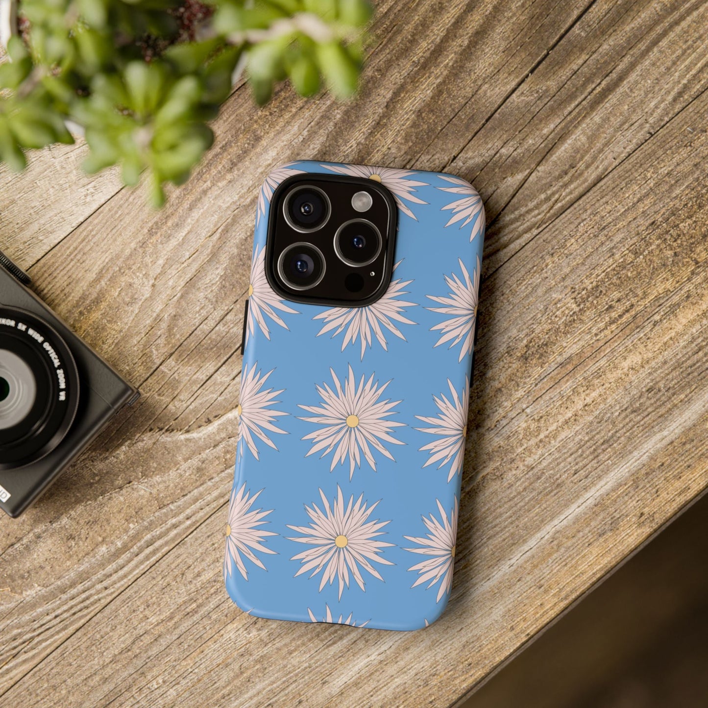 Blue daisy pattern phone case with white floral design on wooden surface
