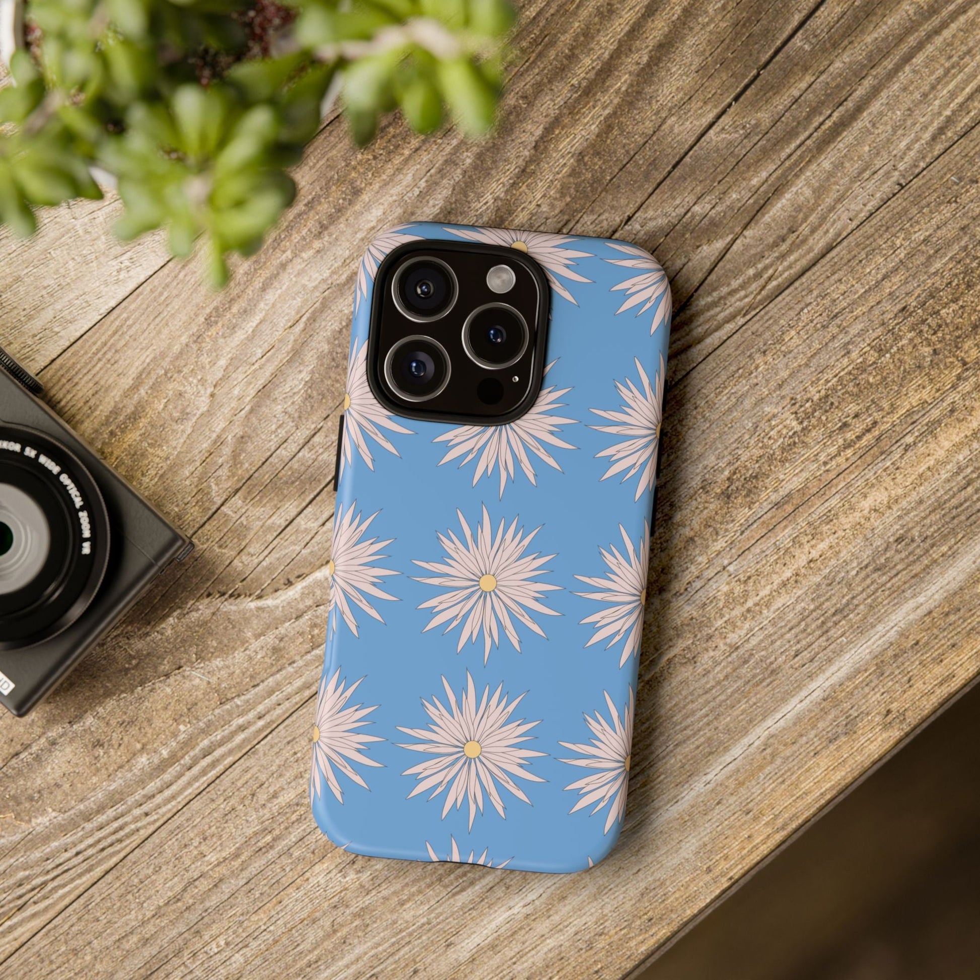 Blue daisy pattern phone case with white floral design on wooden surface