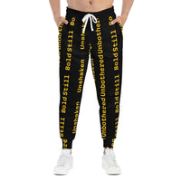 Eco-friendly black joggers with bold yellow "Unbothered Unshaken Bold Still" text, adjustable white drawstring, side pockets, and tapered ankle cuffs.