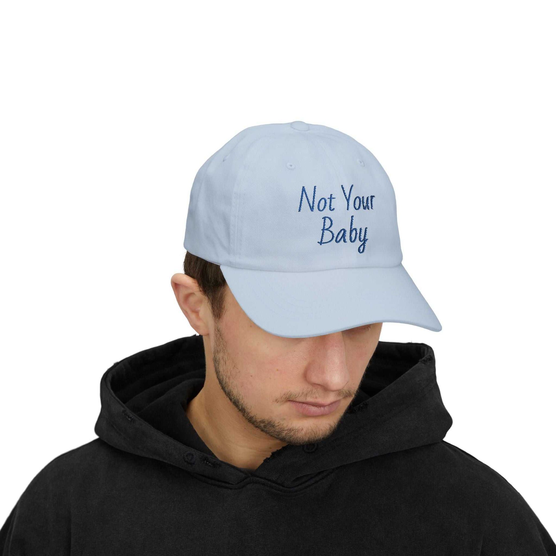 Classic Cap with Not Your Baby embroidery in light blue worn by man in black hoodie