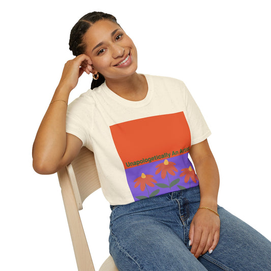 Woman wearing Unapologetically An Artist T-Shirt with floral and colorful graphic design sitting on chair