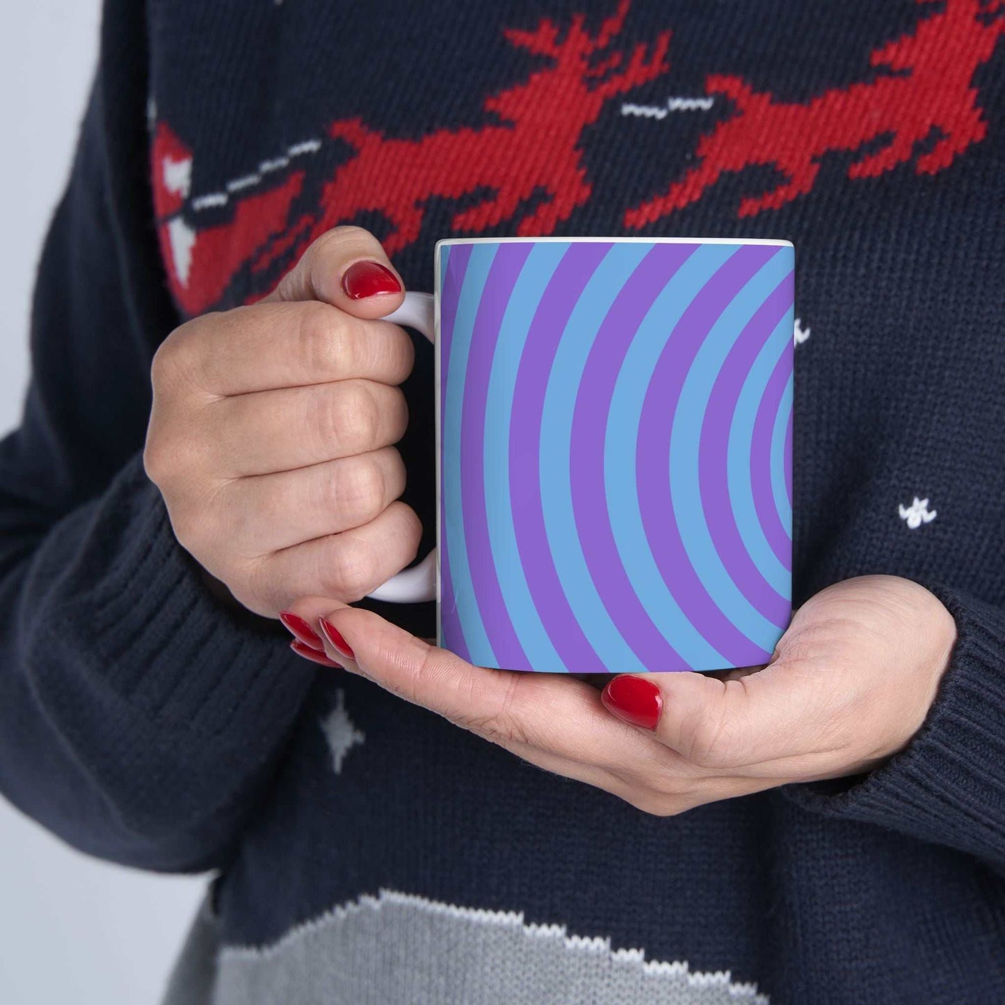 Vibrant Spiral Ceramic Mug with blue and purple spiral design held by person wearing festive sweater