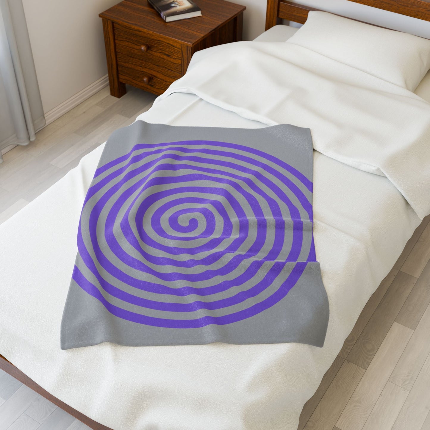 Plush blanket with purple spiral design on gray background on white bed in cozy bedroom