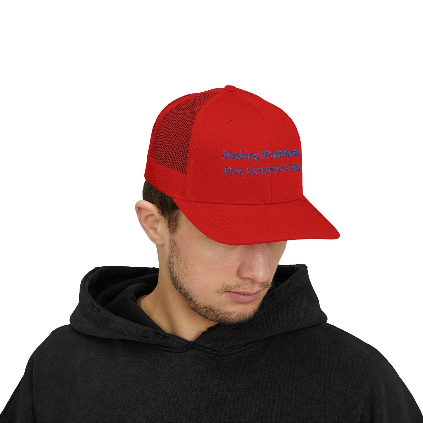 Red snapback trucker cap with mesh back and embroidered text worn by man in black hoodie